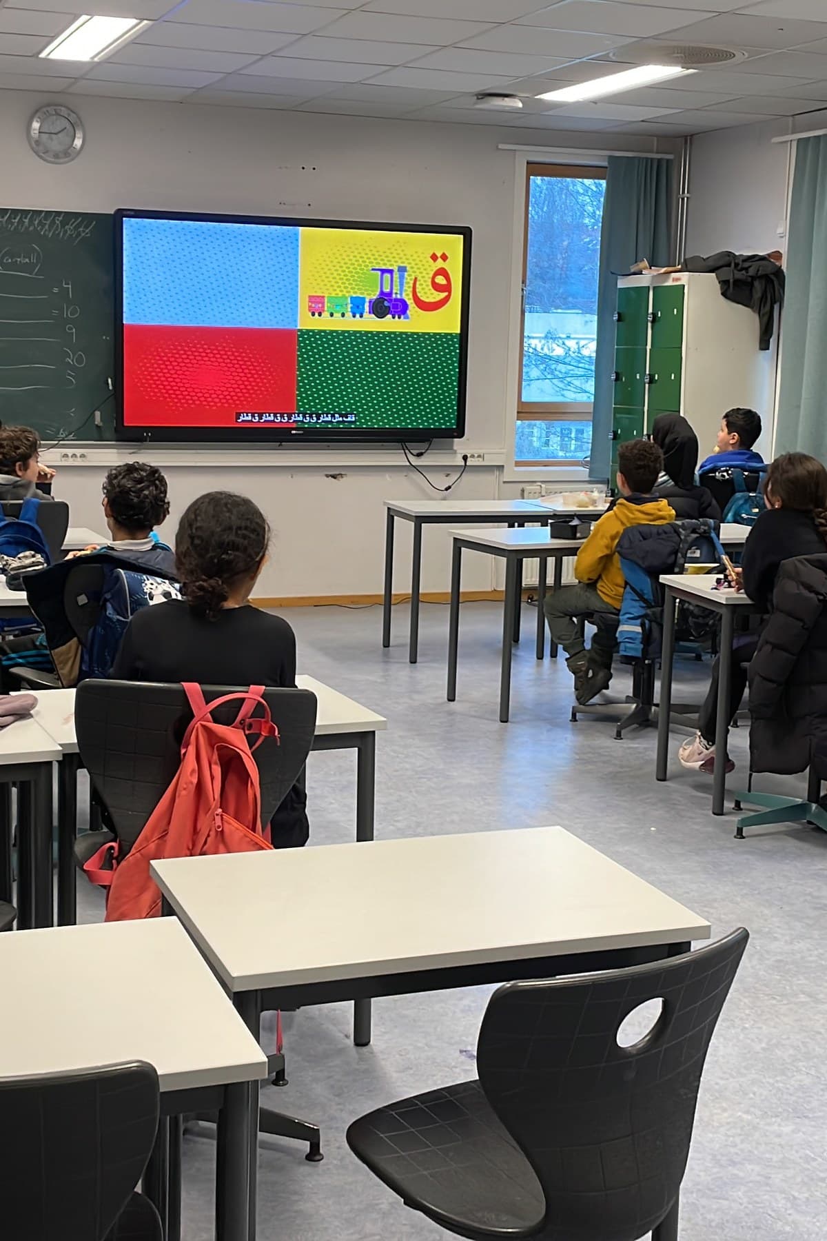 Elever i et klasserom ser på en skjerm med arabiske bokstaver